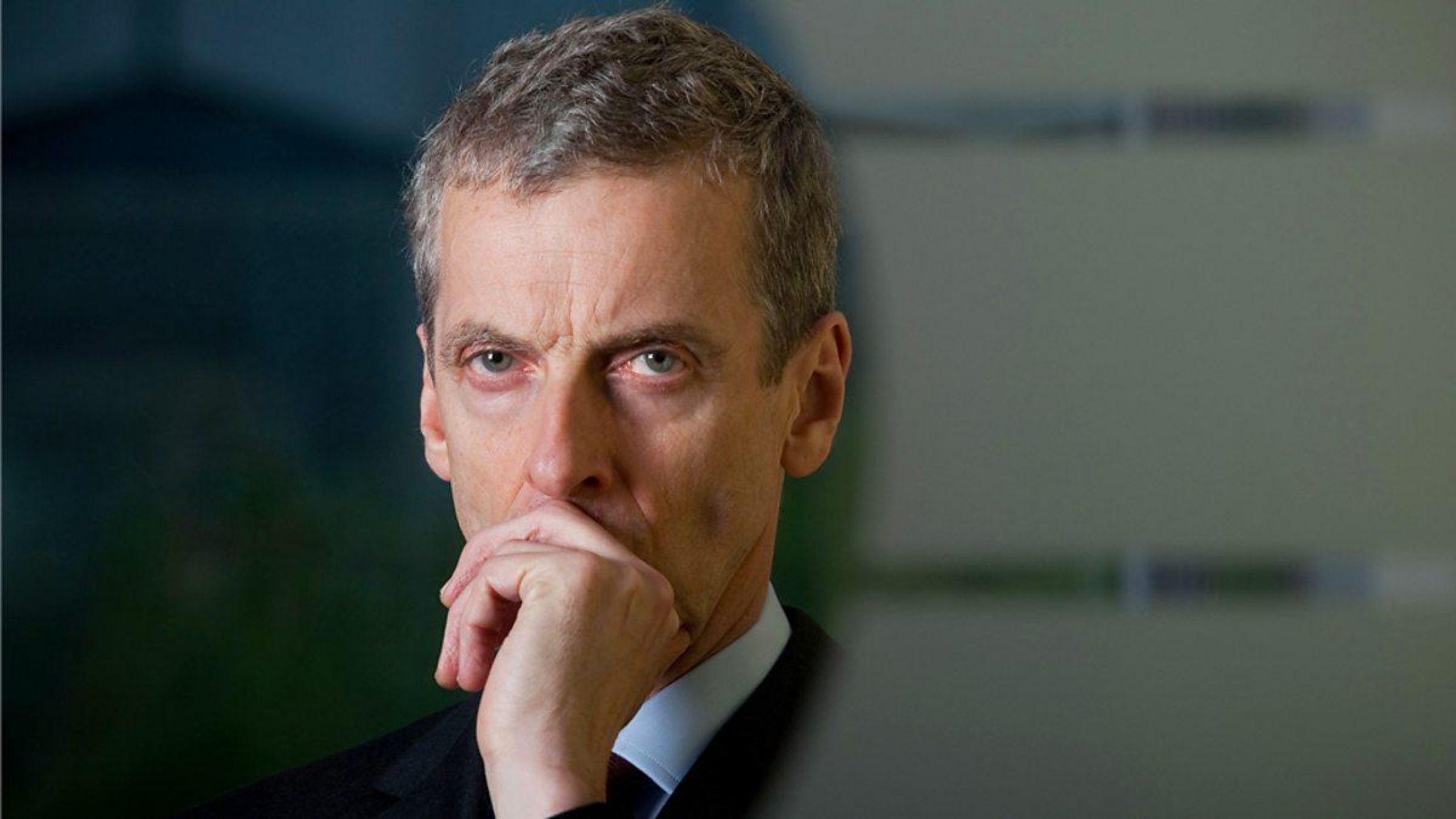 Headshot of Peter Capaldi deep in thought against a blurred background