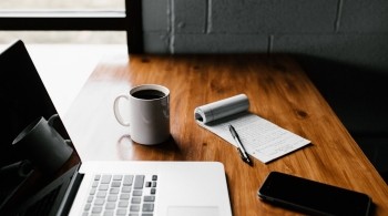 Desk with laptop, phone and notebook on it