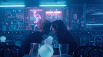 Two woman leaning into kiss in an empty bar
