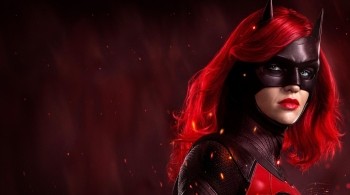 A woman with flowing red hair wearing the classic batman mask 